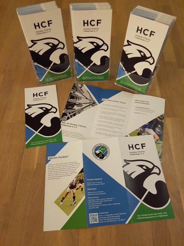 Das Bild zeigt den neuen Flyer des HCF e. V. Er ist in Flyerhaltern gesteckt und liegt auch aufgefaltet mit Vor- und Rückseite auf dem Tisch.